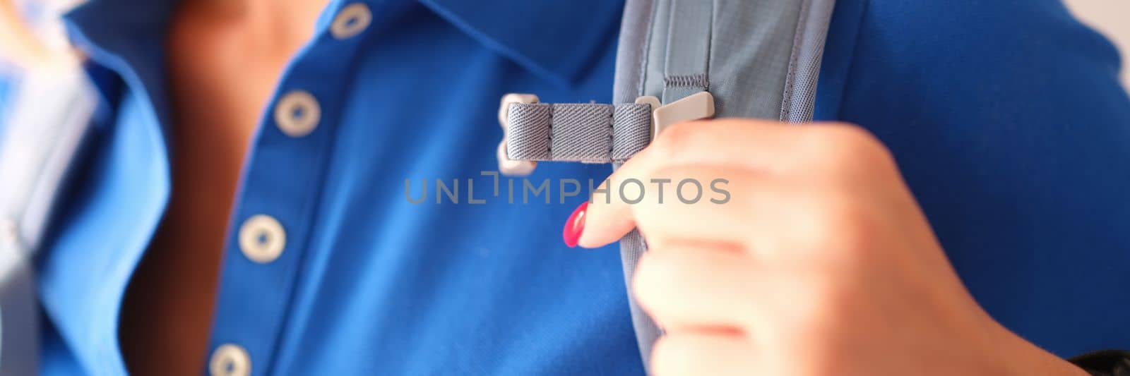 Closeup of woman in blue polo and gray harness of sports backpack. Choosing quality backpack concept