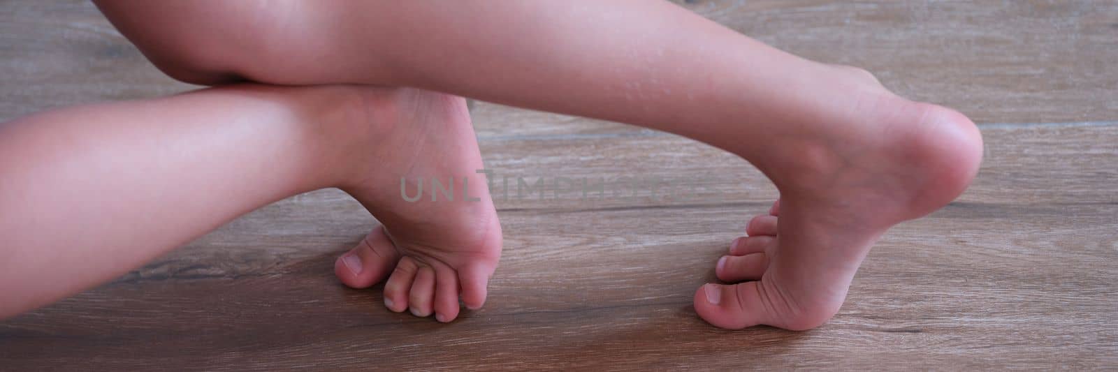 Children feet slide on wooden laminate at home. Floor covering for kids concept