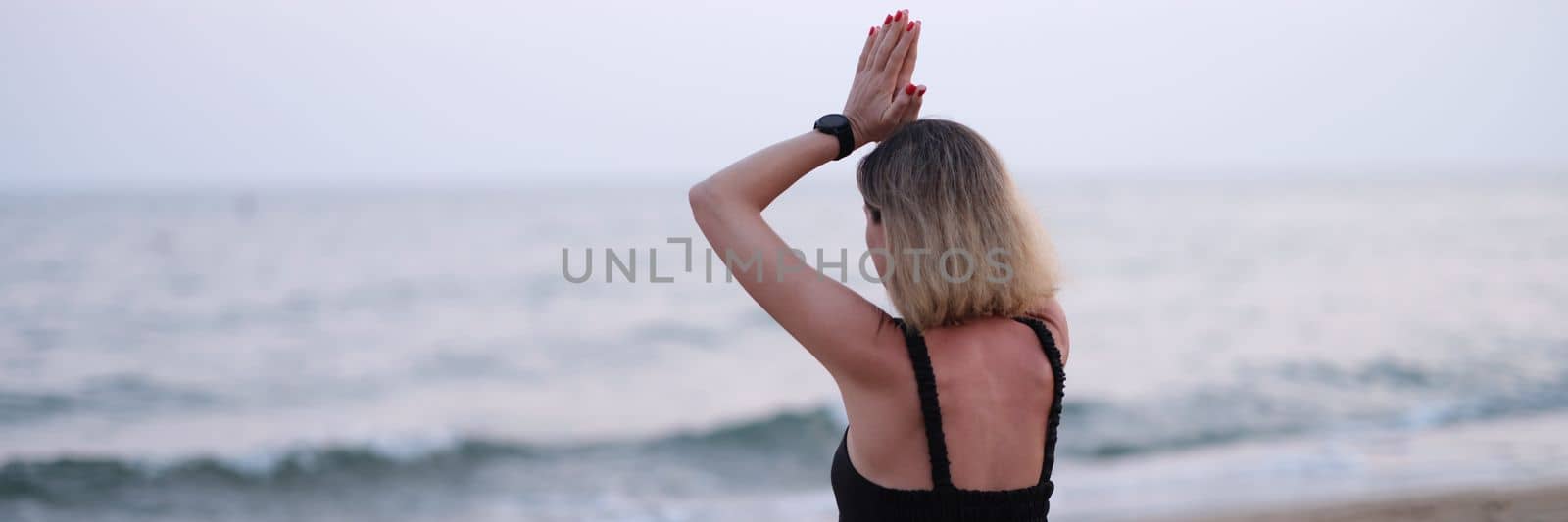 Meditating yoga woman sits on seaside beach. Relaxing meditation on beach concept