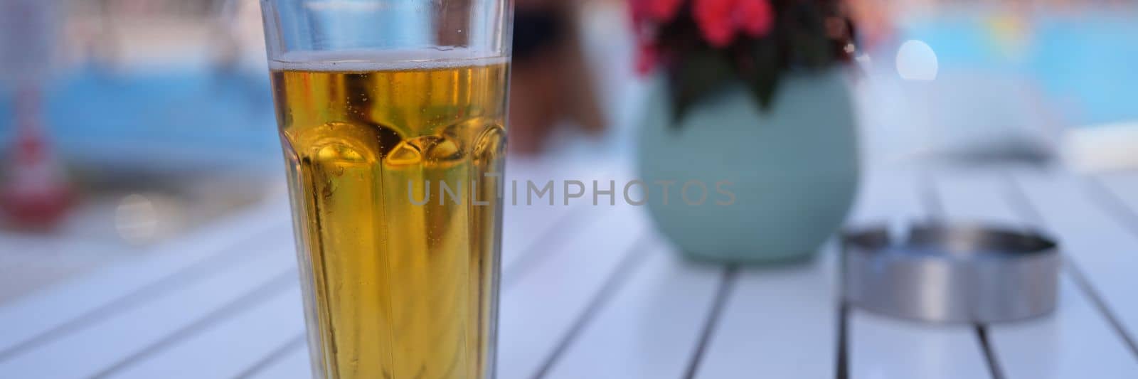 One cold alcoholic beer in transparent glass on sunny day by pool by kuprevich
