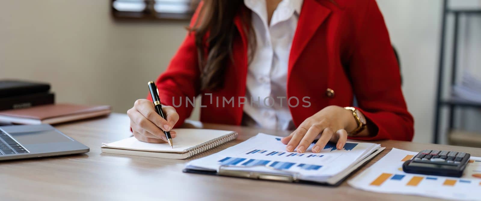 close-up shot of accountant using calculator while taking notes on office desk.