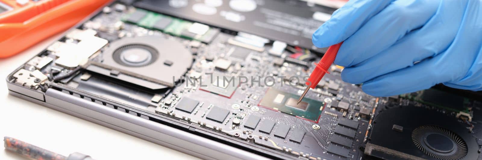 Technician measures the voltage on motherboard of computer electronic digital multimeter. PC diagnostics with multimeter concept