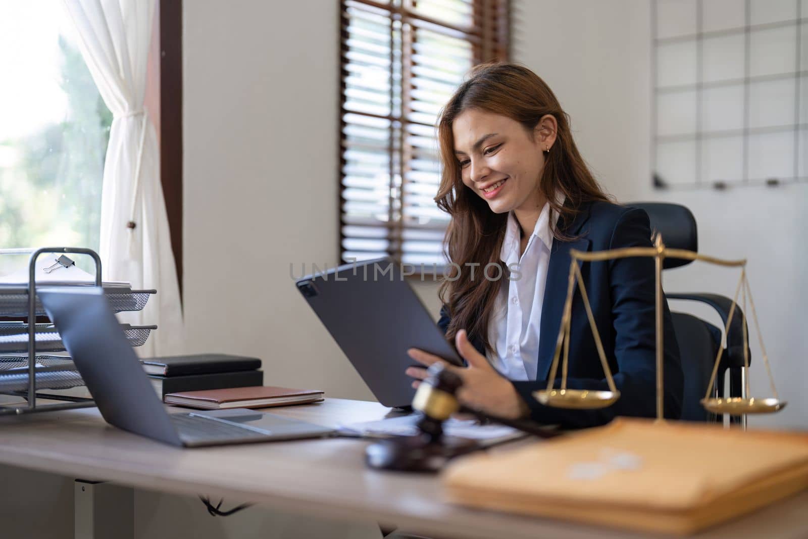 Attractive young lawyer in office Business woman and lawyers discussing contract papers with brass scale on wooden desk in office. Law, legal services, advice, Justice and real estate concept by nateemee