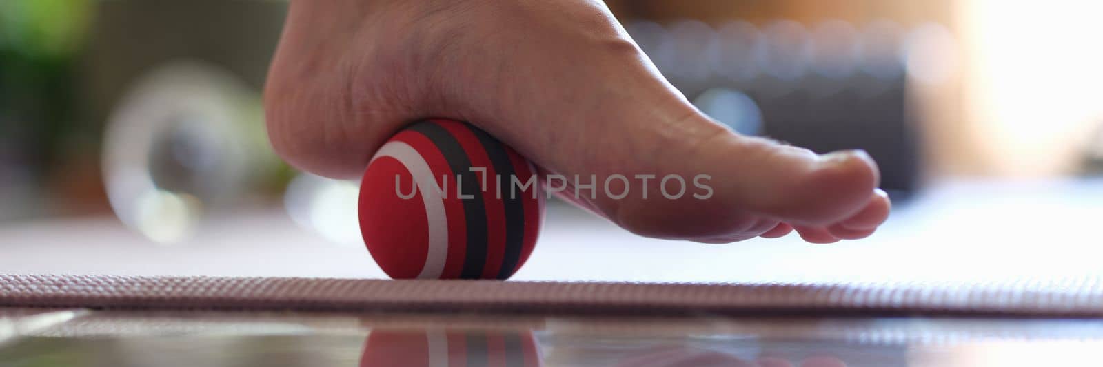 Massage ball applies pressure to painful area on foot. Self-massage and exercises with massage ball for legs concept