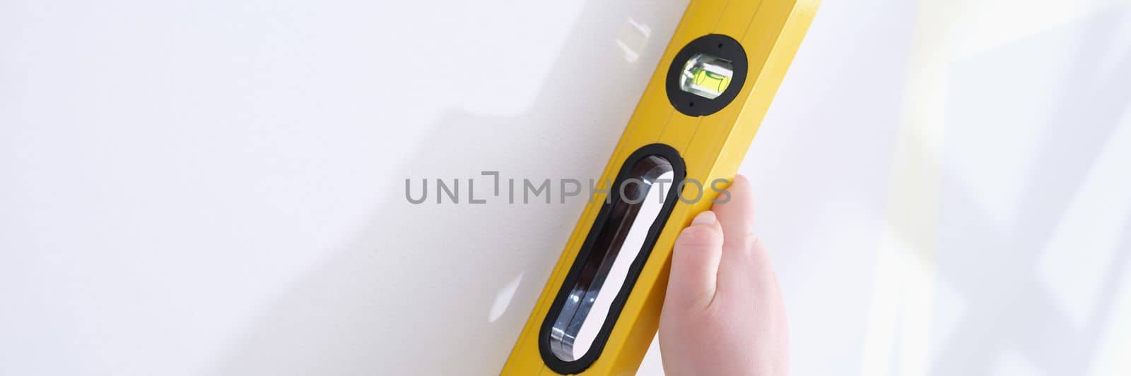 Professional yellow measuring device for level and evenness of wall. Builder makes repairs in apartment concept