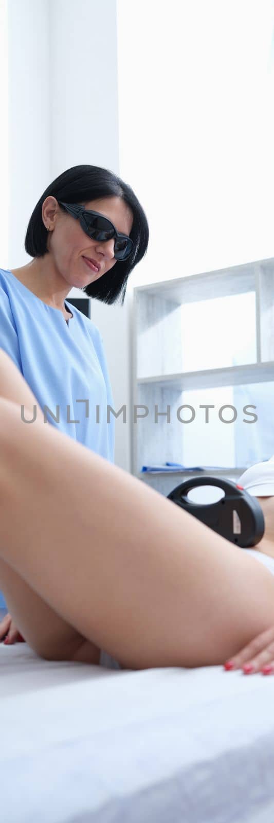Doctor does laser hair removal on client legs and bikini. Long-term hair removal and laser hair removal concept