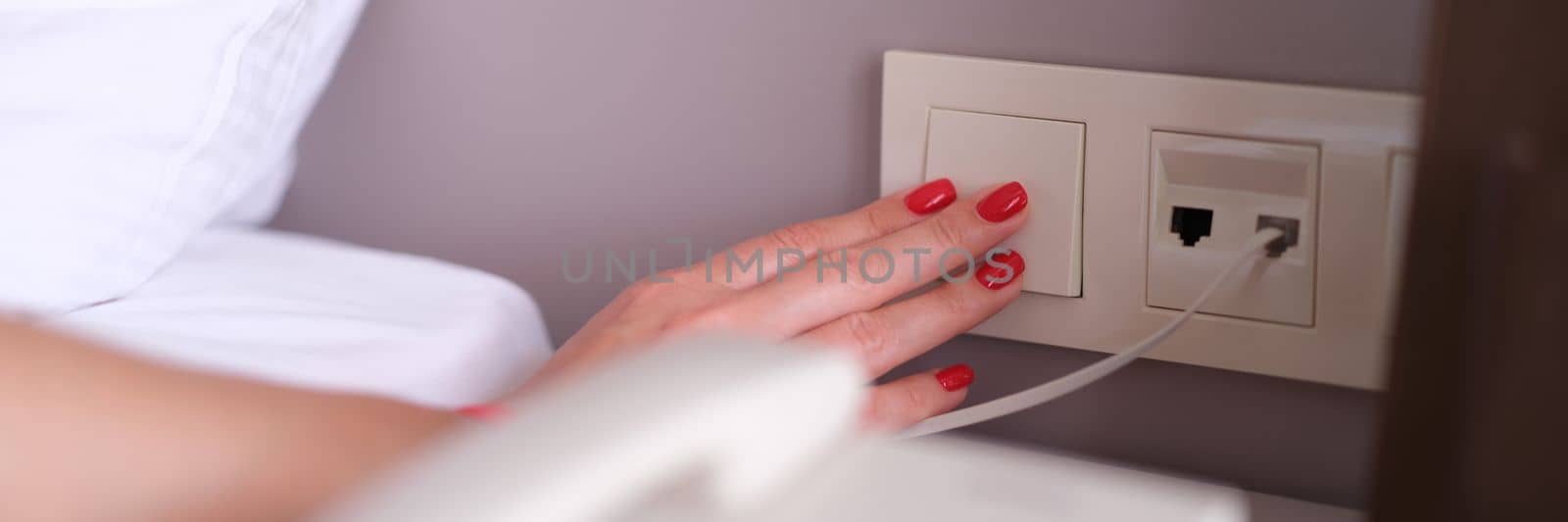 Woman hand turns off or turns on light with white switch closeup by kuprevich