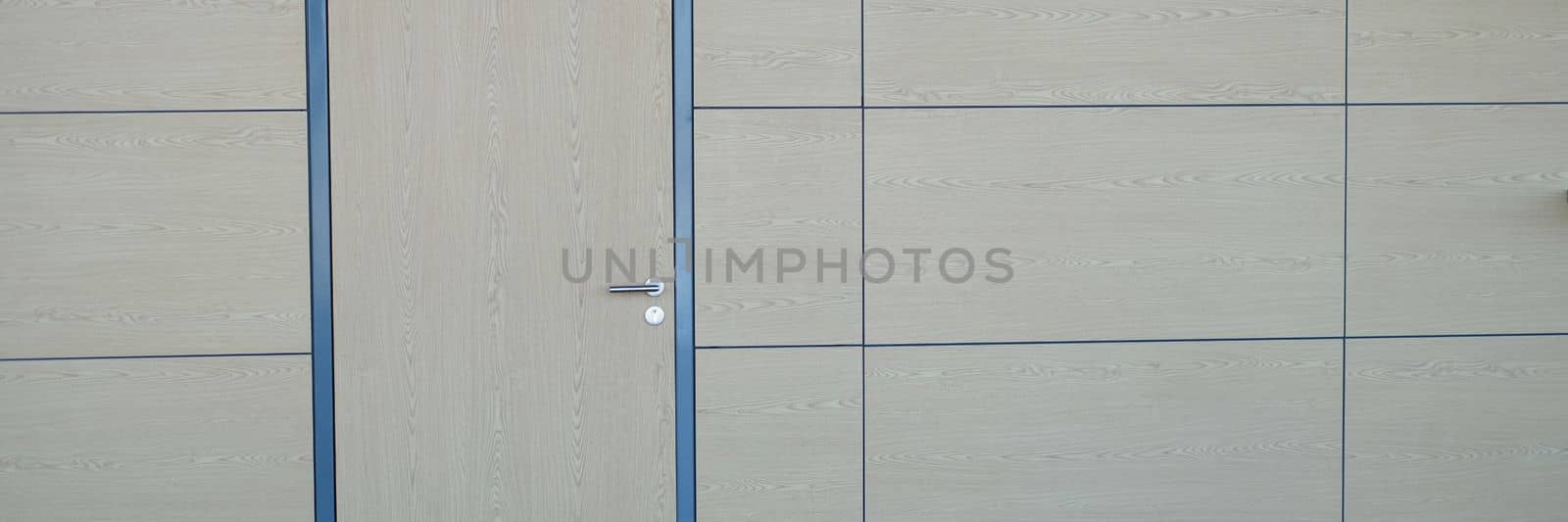 Modern office lobby with wooden walls brown door white wall and vertical poster. Design concept of doors in airport station business center