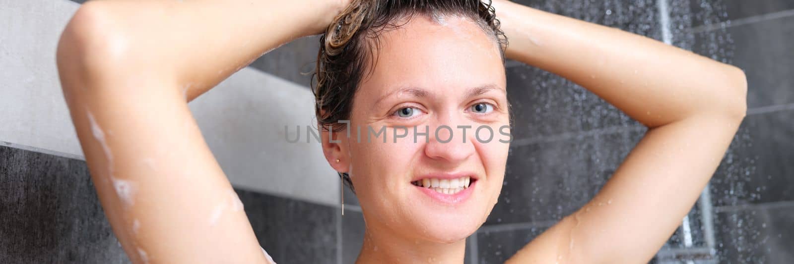 Young beautiful woman under the shower in bathroom. Portrait of happy joyful woman in the shower