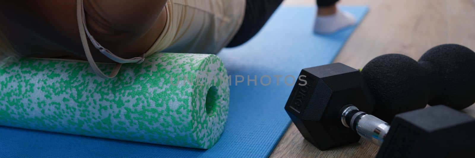 Closeup of woman riding cork massage roller to relieve tension in back muscles by kuprevich