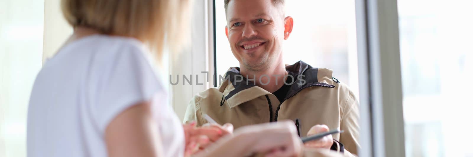 Smiling courier man delivers parcel to woman. Home delivery service concept