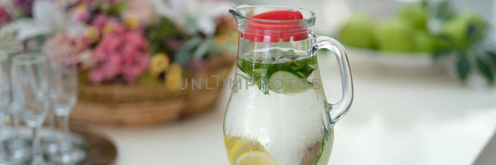 Infused detox water with cucumber, lemon and mint in jug on table. Diet healthy eating and weight loss concept