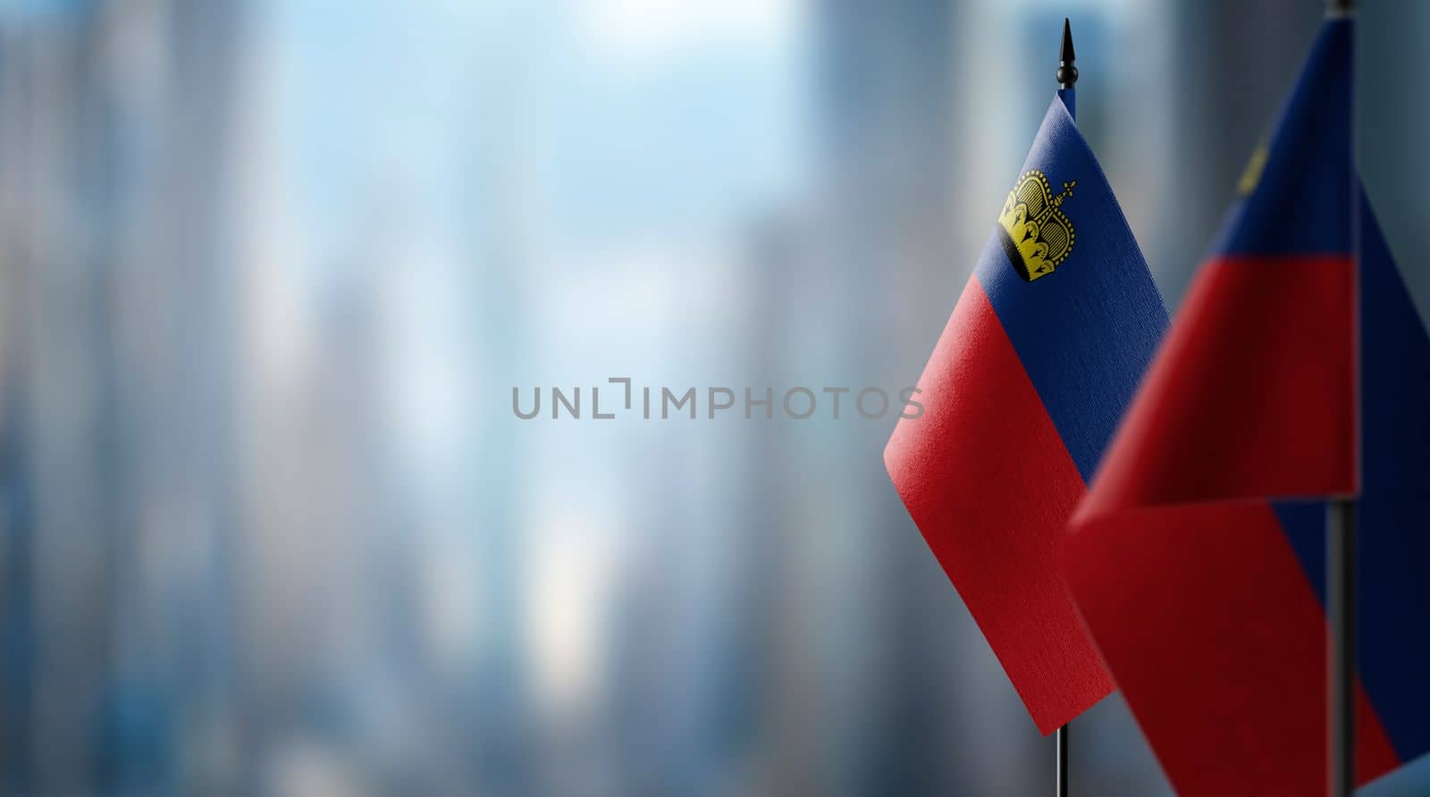 Small flags of the Liechtenstein on an abstract blurry background.