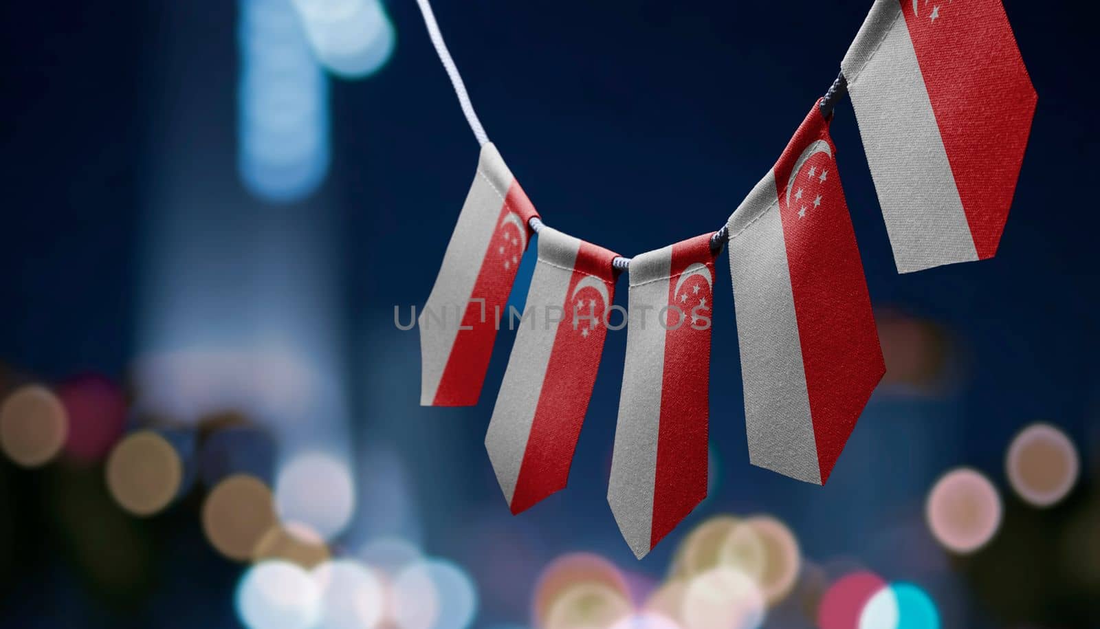 A garland of Singapore national flags on an abstract blurred background by butenkow
