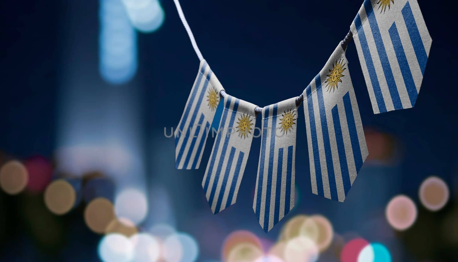 A garland of Uruguay national flags on an abstract blurred background.