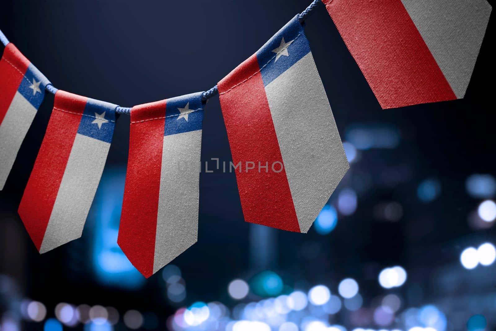 A garland of Chile national flags on an abstract blurred background.