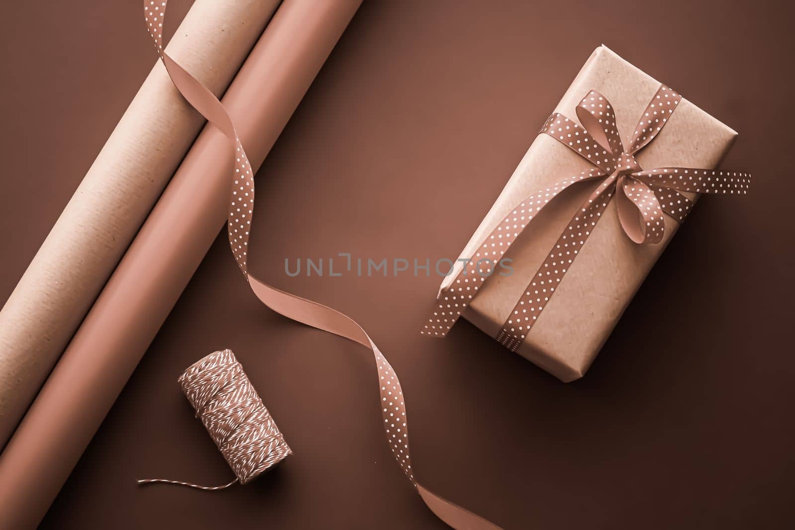 Gifts preparation, birthday and holidays gift giving, craft paper and ribbons for gift boxes on chocolate background as wrapping tools and decorations, diy presents as holiday flat lay design.