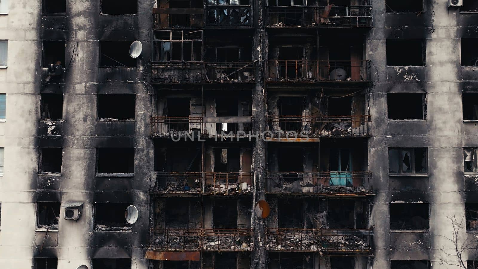 A burnt-out high-rise in the war zone. Damage to a residential building as a result of artillery shelling. War in residential areas, broken windows and burned apartments. Armed conflict in Ukraine.