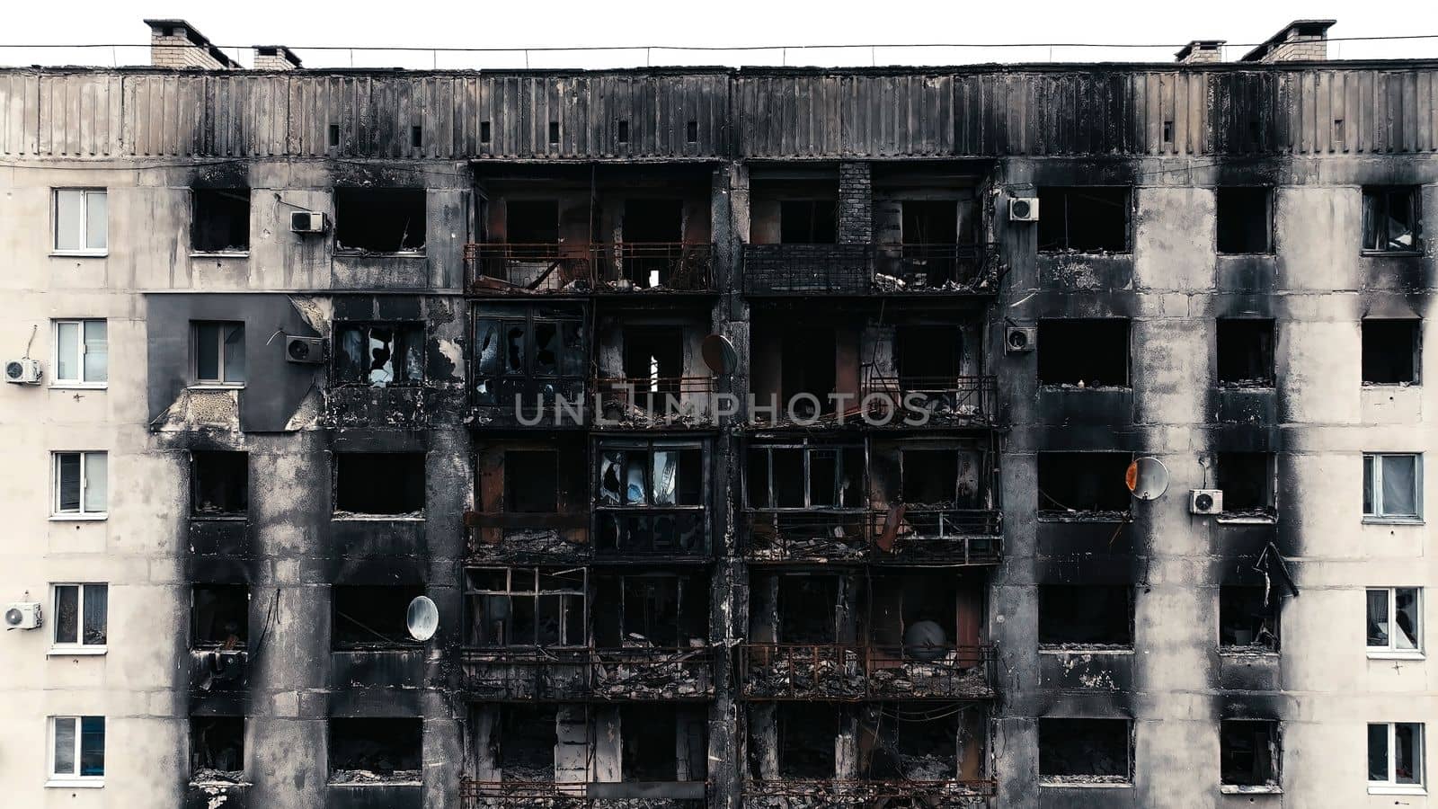 A burnt-out high-rise in the war zone. Damage to a residential building as a result of artillery shelling. War in residential areas, broken windows and burned apartments. Armed conflict in Ukraine.