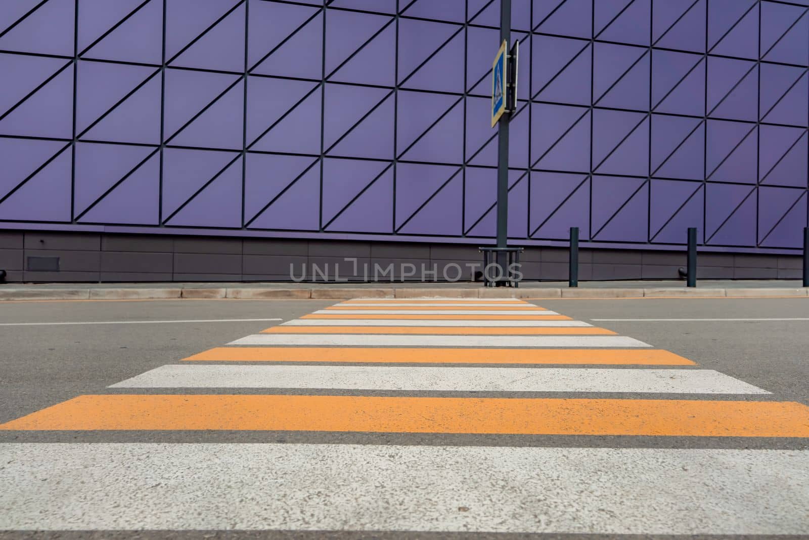 Pedestrian crosswalk on a renovated paved road, to the beginning of the shopping complex. Pedestrian crosswalk on the street for safety, white and yellow stripes