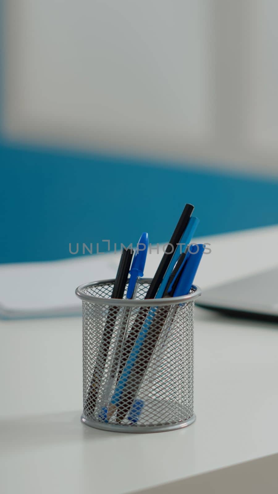 Close up of pens and laptop on white desk in empty cabinet by DCStudio