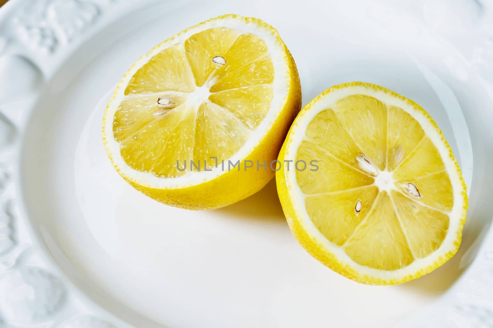 Yellow fresh lemon cut in half on white plate