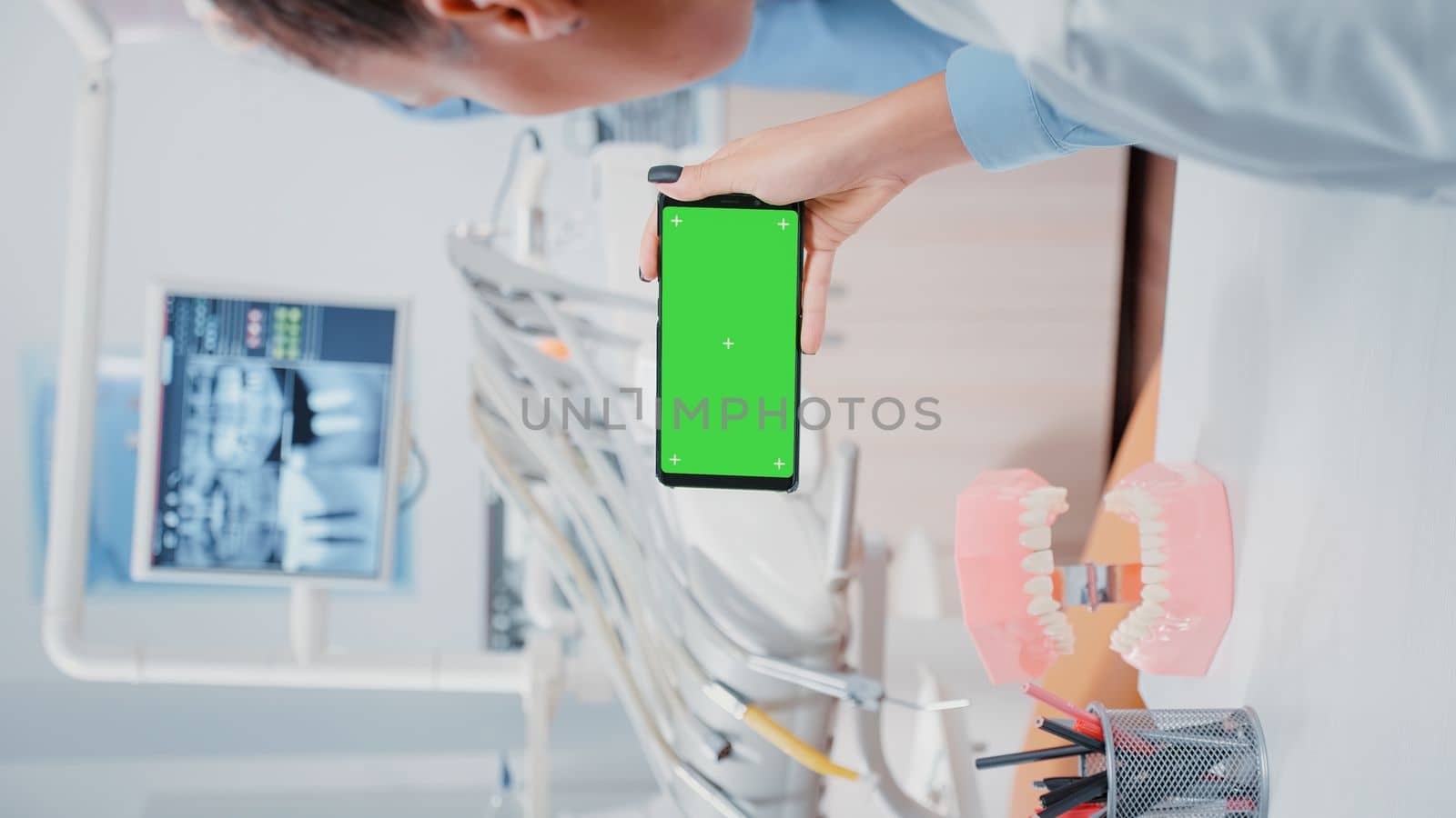 Vertical video: Dentist looking at mobile phone with green screen by DCStudio