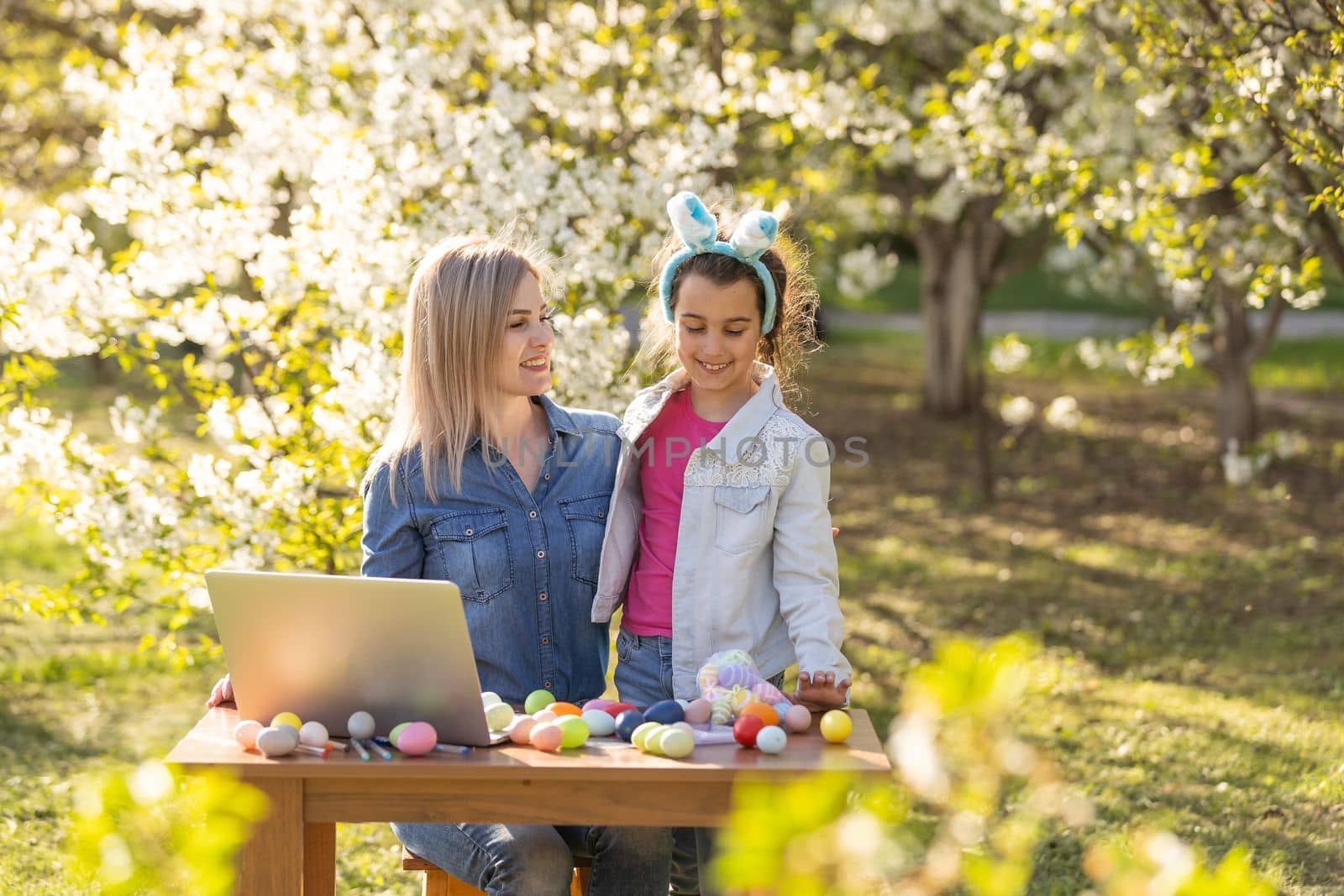 mother and daughter paint easter eggs with laptop, record lessons on a webcam with a laptop. mother and daughter are preparing for the holiday together. by Andelov13