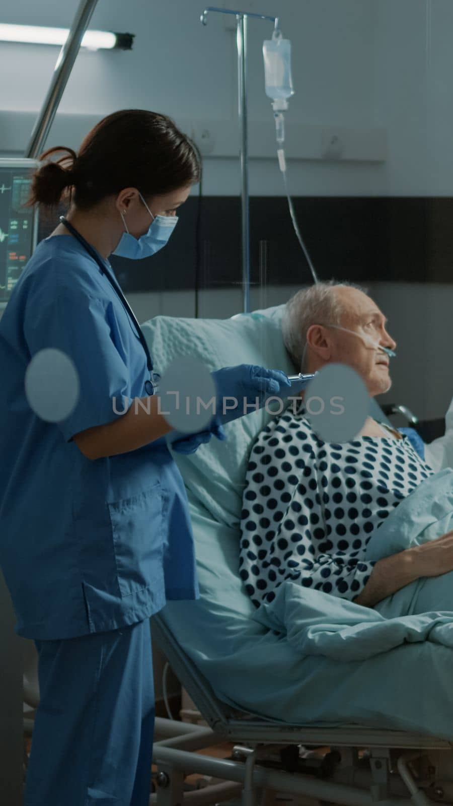 Multi ethnic medical staff talking about treating patient in hospital ward bed at recovery facility. Sick old man with nasal oxygen tube in intensive care room seeking treatment for healthcare