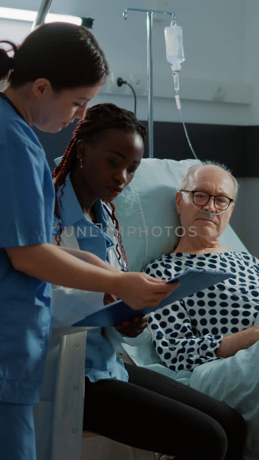 African american doctor talking to sick patient in bed at hospital ward for treating health problems and injury. Old man asking medic and nurse about intensive care and illness recovery