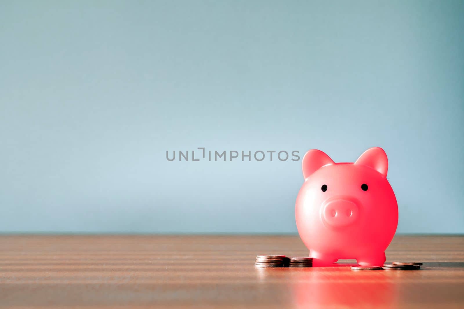 Piggy Bank and a few coins on gray background. The concept of saving less saving money piggy bank and financial planning concept, broke and poor copy space close up