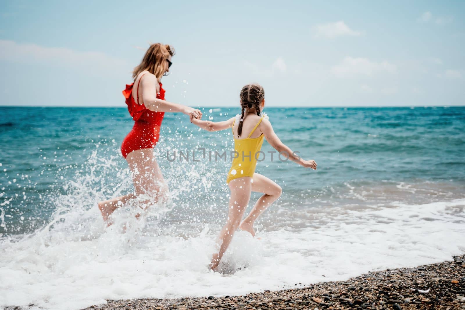 Happy loving family mother and daughter having fun together on the beach. Mum playing with her kid in holiday vacation next to the ocean - Family lifestyle and love concept.