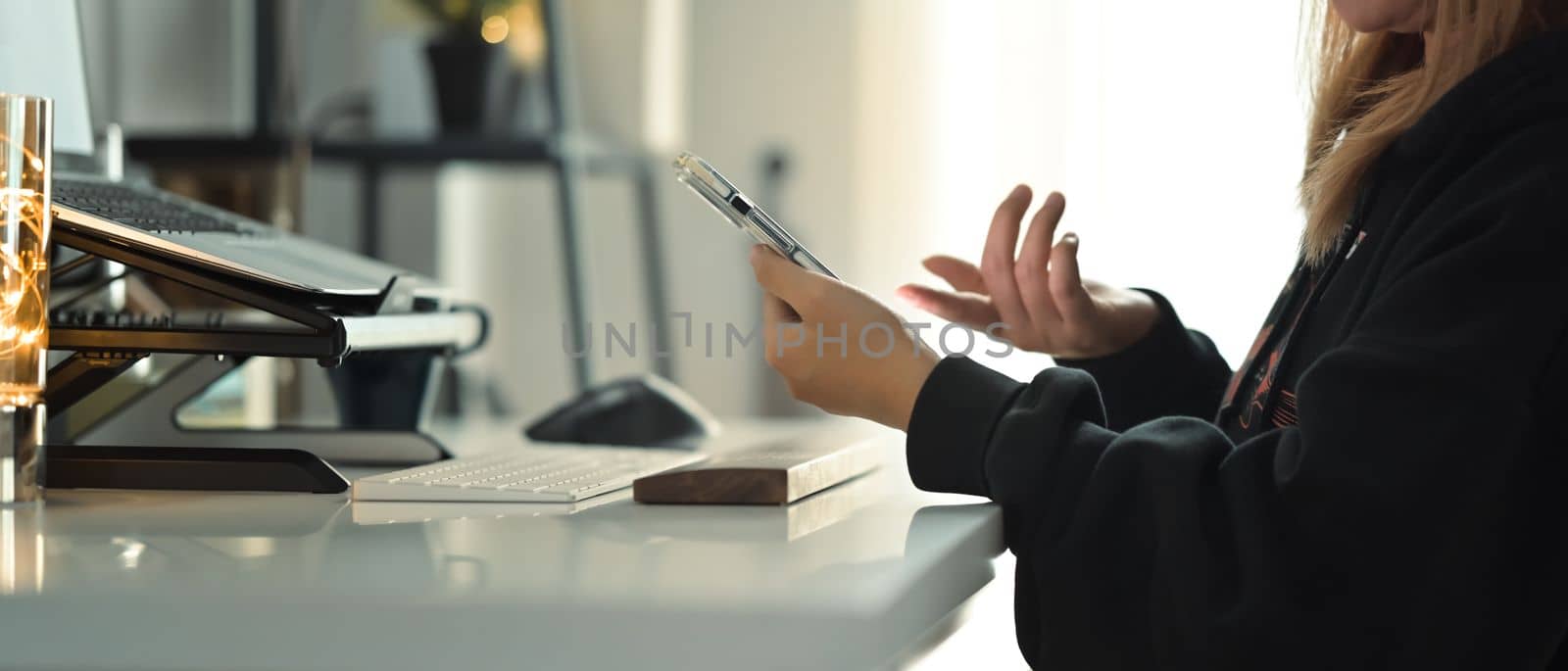 Cropped shot of female freelancer using mobile phone while working remotely on online project at home.
