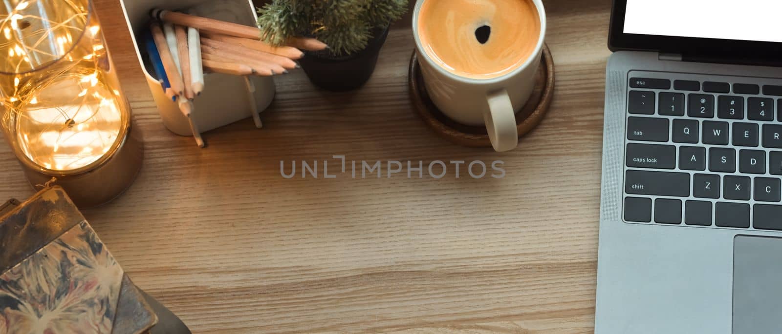 From above view of laptop, vintage book, pencil holder and cup of coffee on wooden table. Copy space for your text by prathanchorruangsak