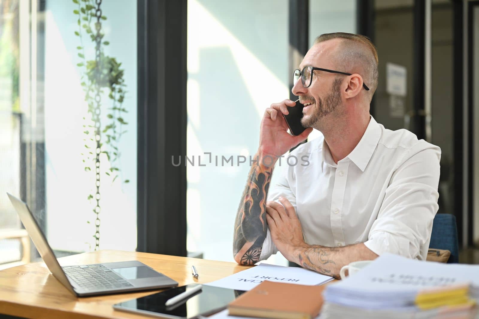 Portrait of a successful caucasian man having a business conversation and looking through office window by prathanchorruangsak