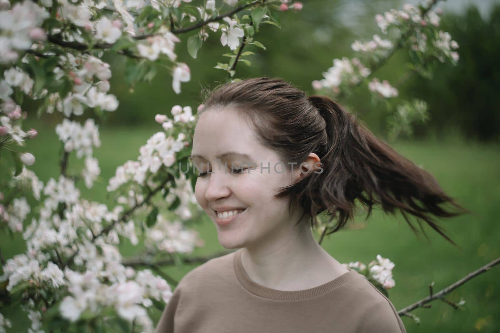 Beautiful young woman near blooming spring tree. Youth, love, fashion, romantic and lifestyle concept by paralisart