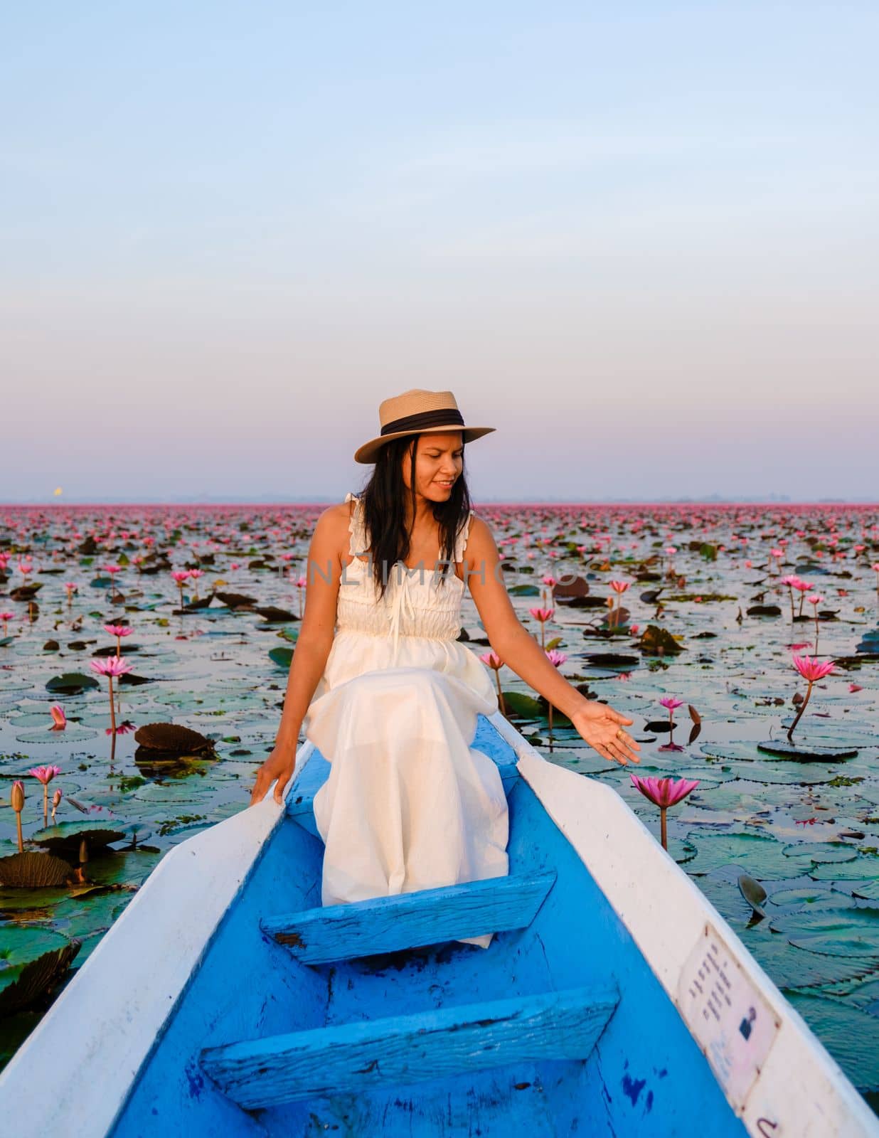 Thai women in a boat at the Red Lotus Sea Kumphawapi full of pink flowers in Udon Thani Thailand. by fokkebok