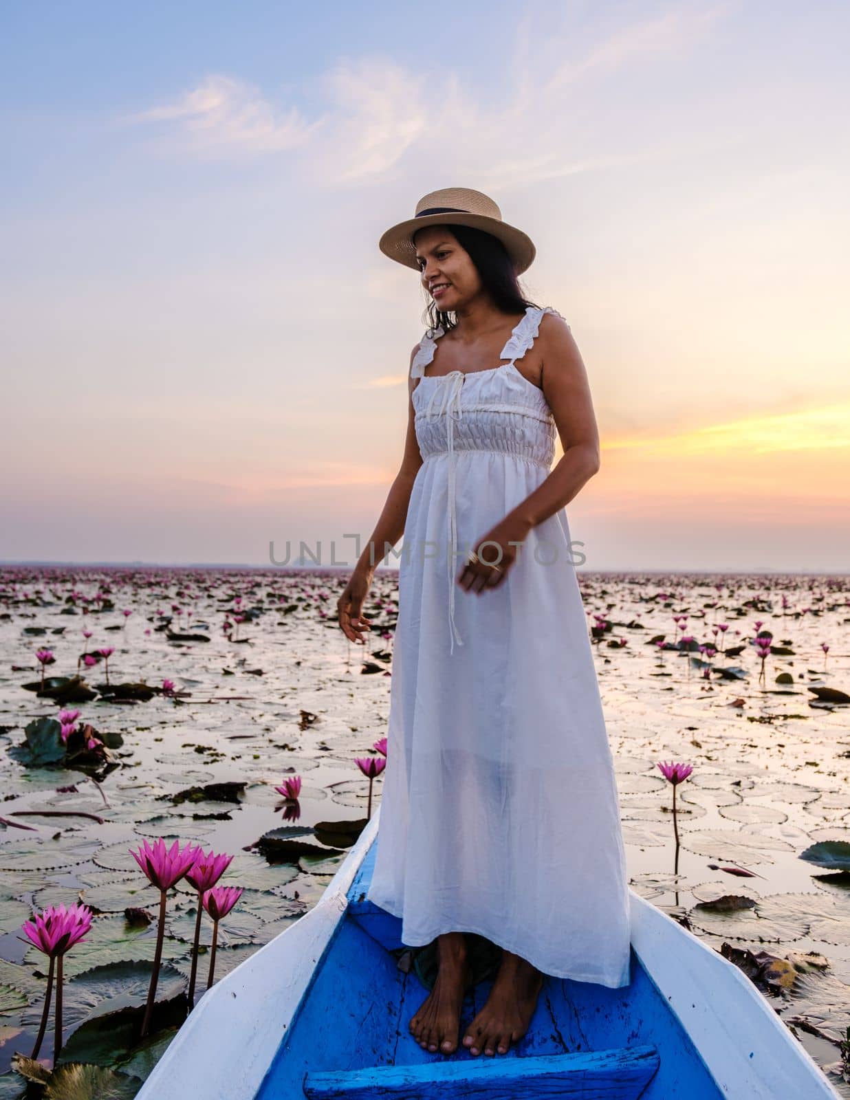 Asian women in a boat at the Beautiful Red Lotus Sea Kumphawapi is full of pink flowers in Udon Thani in northern Thailand. Flora of Southeast Asia.