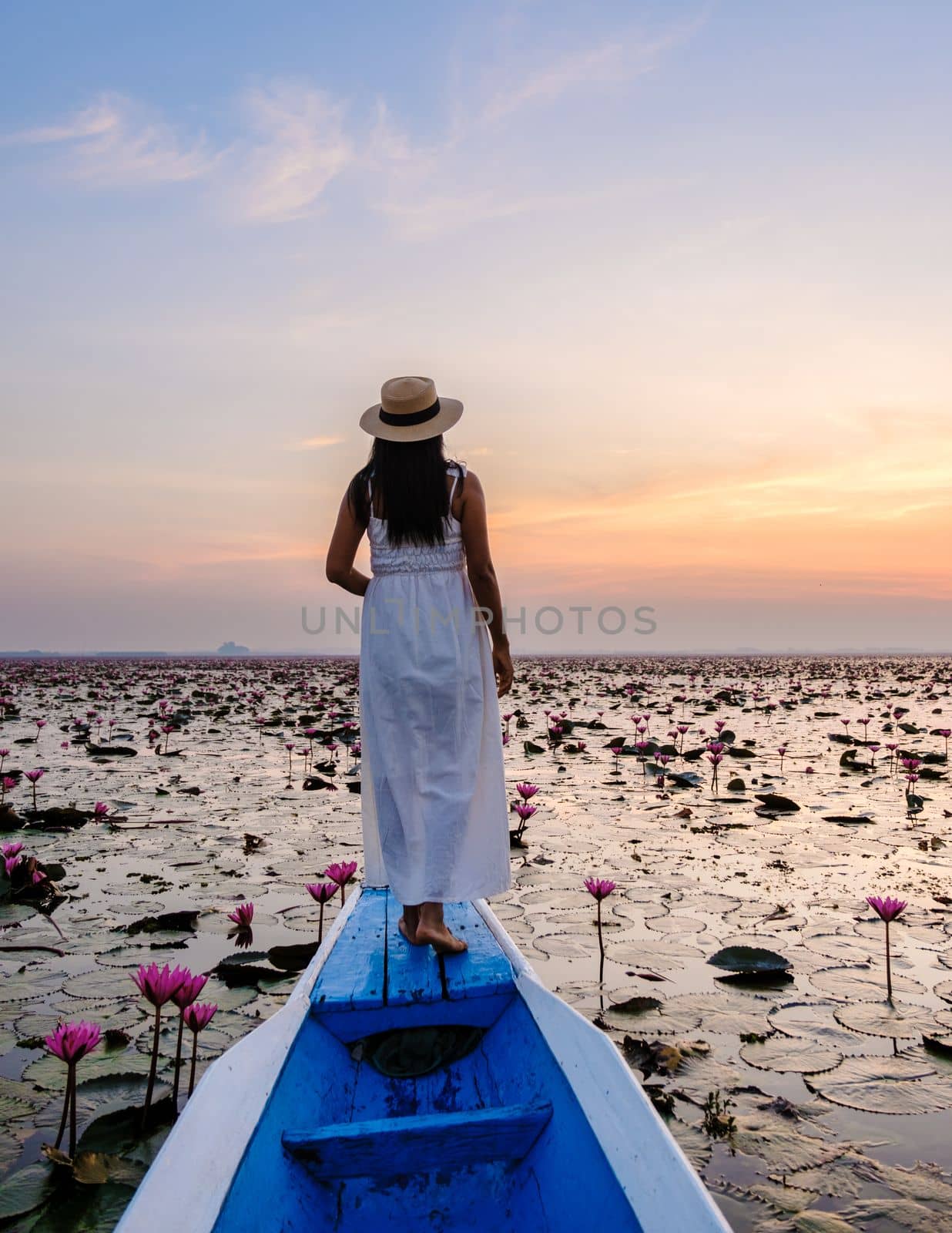 Asian women with a hat in a boat at the Red Lotus Sea full of pink flowers in Udon Thani Thailand. by fokkebok