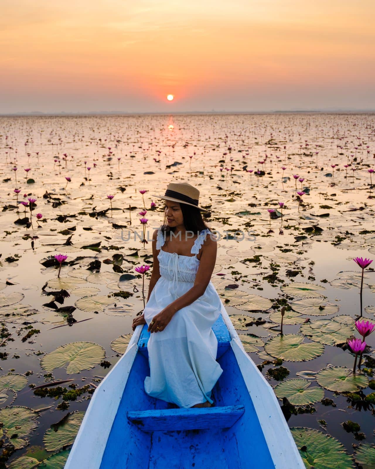 Asian women in a boat at the Beautiful Red Lotus Sea Kumphawapi is full of pink flowers in Udon Thani in Northern Thailand Isaan. Flora of Southeast Asia.