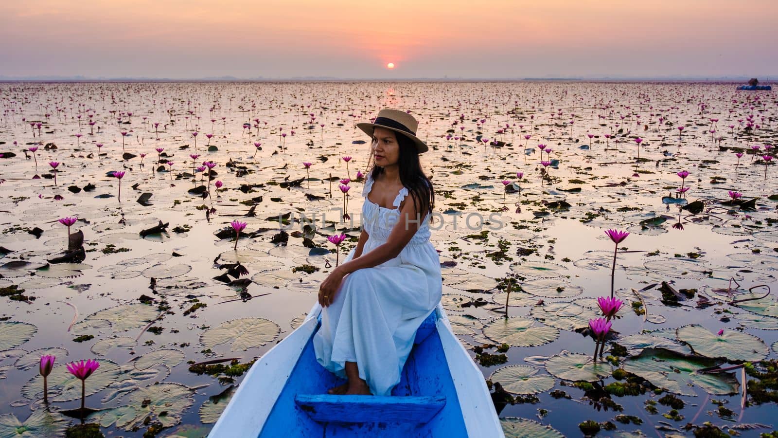 Asian women in a boat at the Red Lotus Sea full of pink flowers in Udon Thani Thailand. by fokkebok