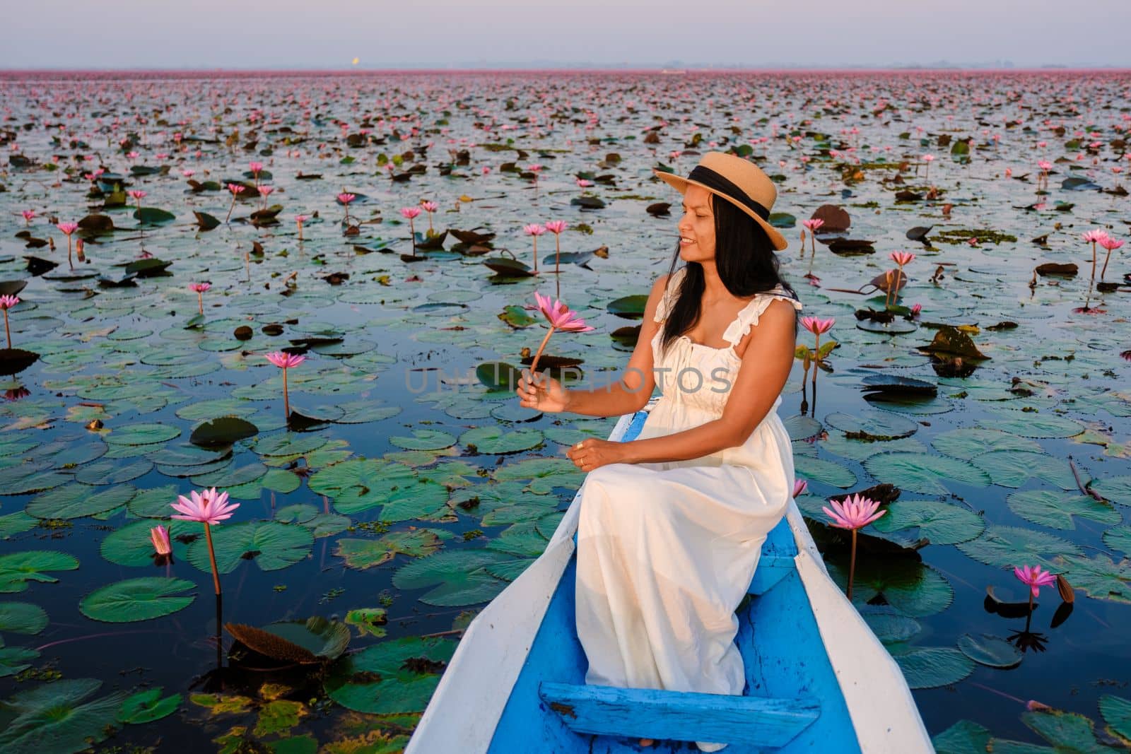 Asian women in a boat at the Red Lotus Sea Kumphawapi full of pink flowers in Udon Thani Thailand. by fokkebok