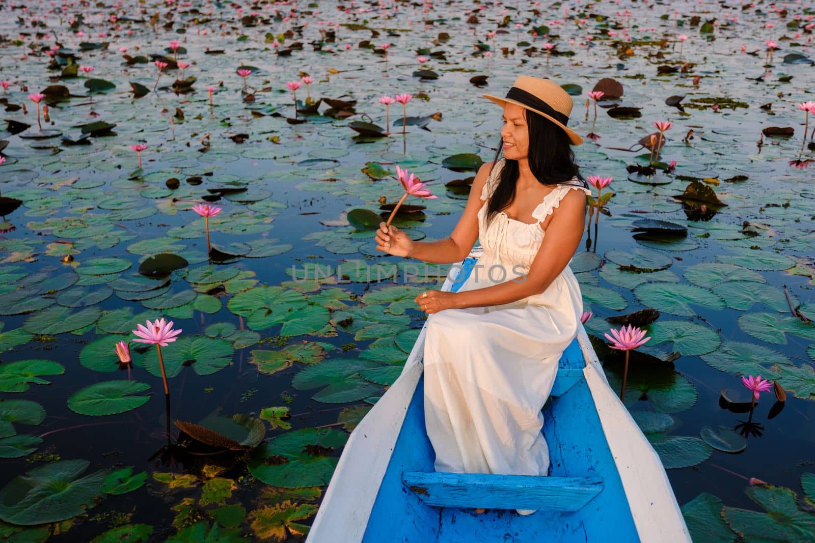 Thai women in a boat at the Red Lotus Sea Kumphawapi full of pink flowers in Udon Thani Thailand. by fokkebok