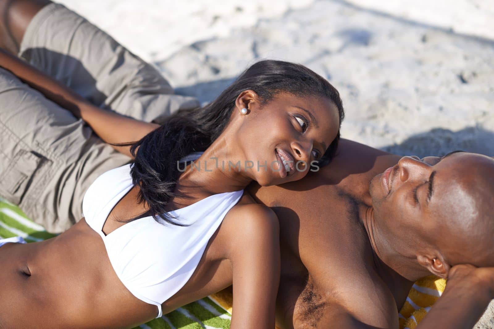 Summer romance is in the air. A loving young african couple relaxing on the beach