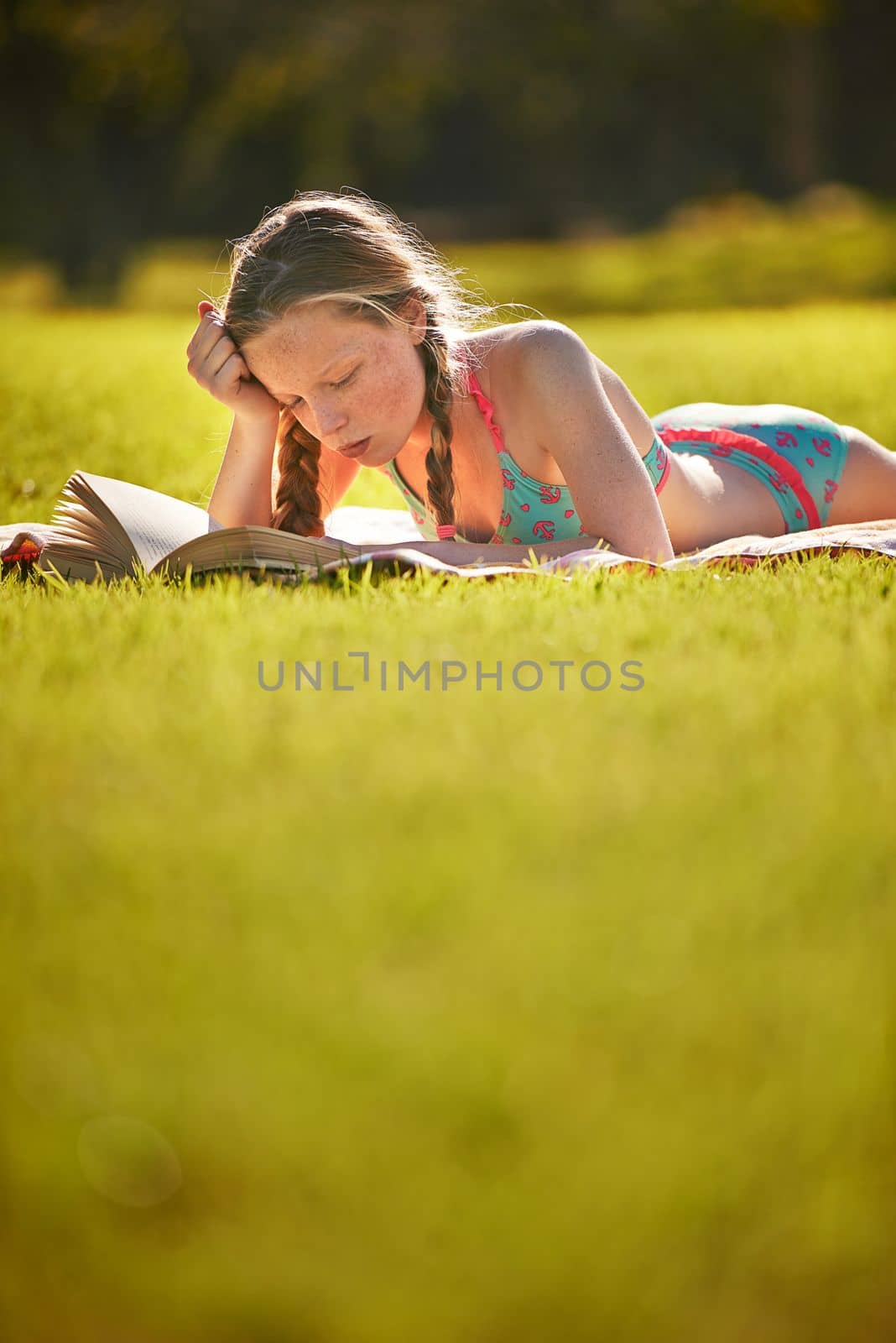 Reading in the summer sun. a young girl reading in the outdoors. by YuriArcurs