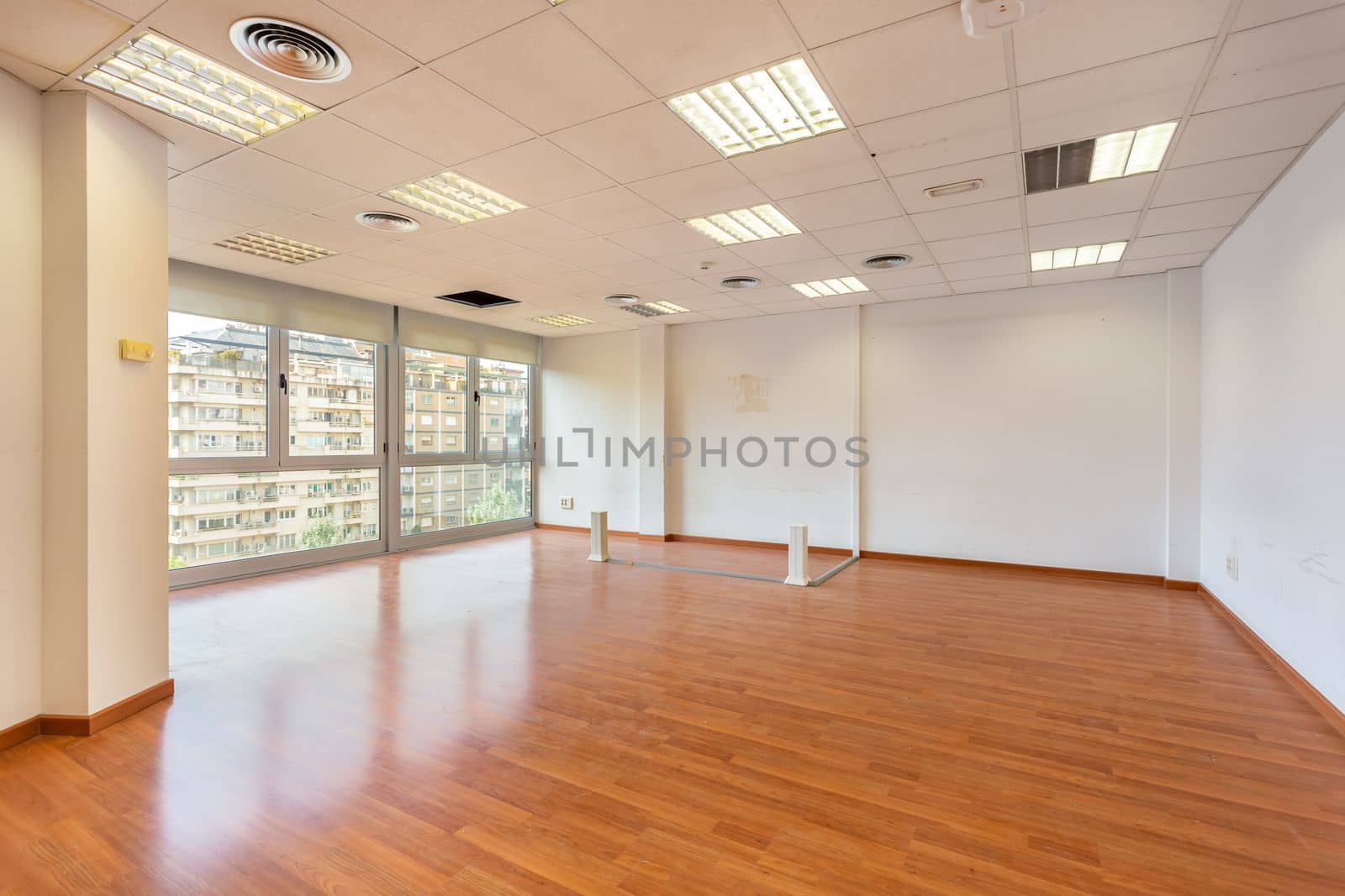 Empty office and fluorescent lamps on the ceiling in need of repair and replacement. Bright office space for rent. Light brown parquet and large panoramic windows in an empty abandoned office. by apavlin