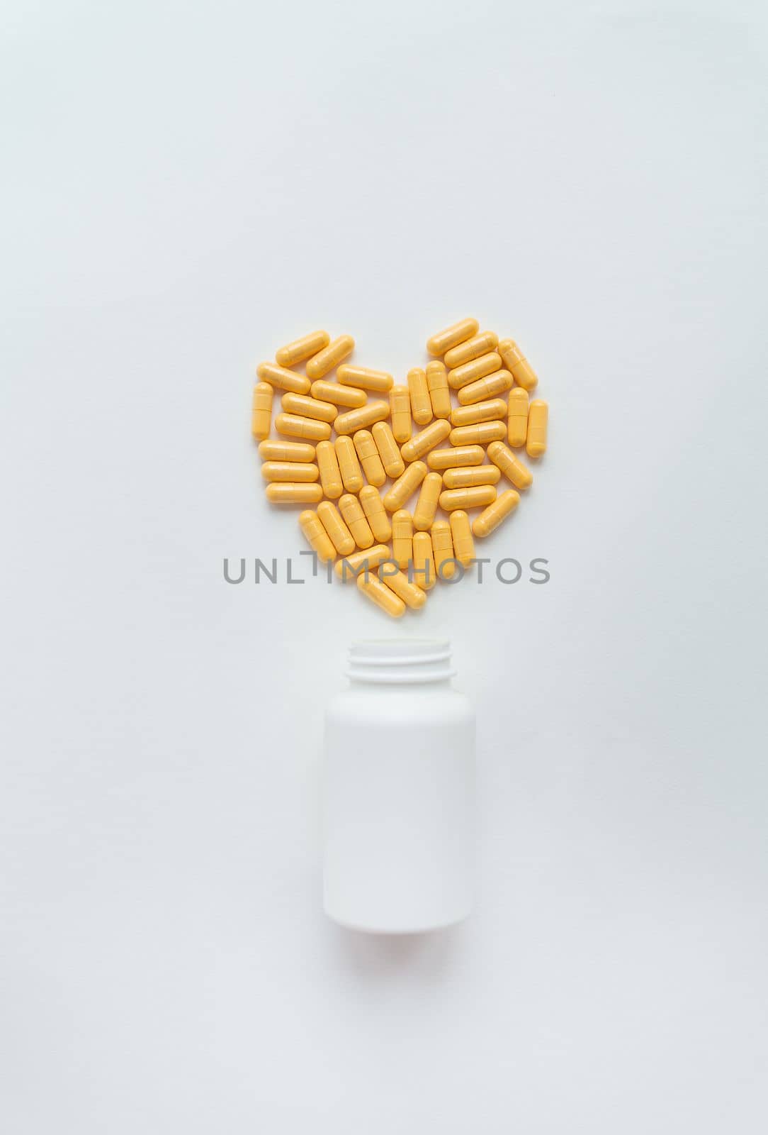 Yellow pills in the shape of a heart, health and heart problems along with a plastic jar. The concept of medicine and healthcare. Place for an inscription, vertical photo