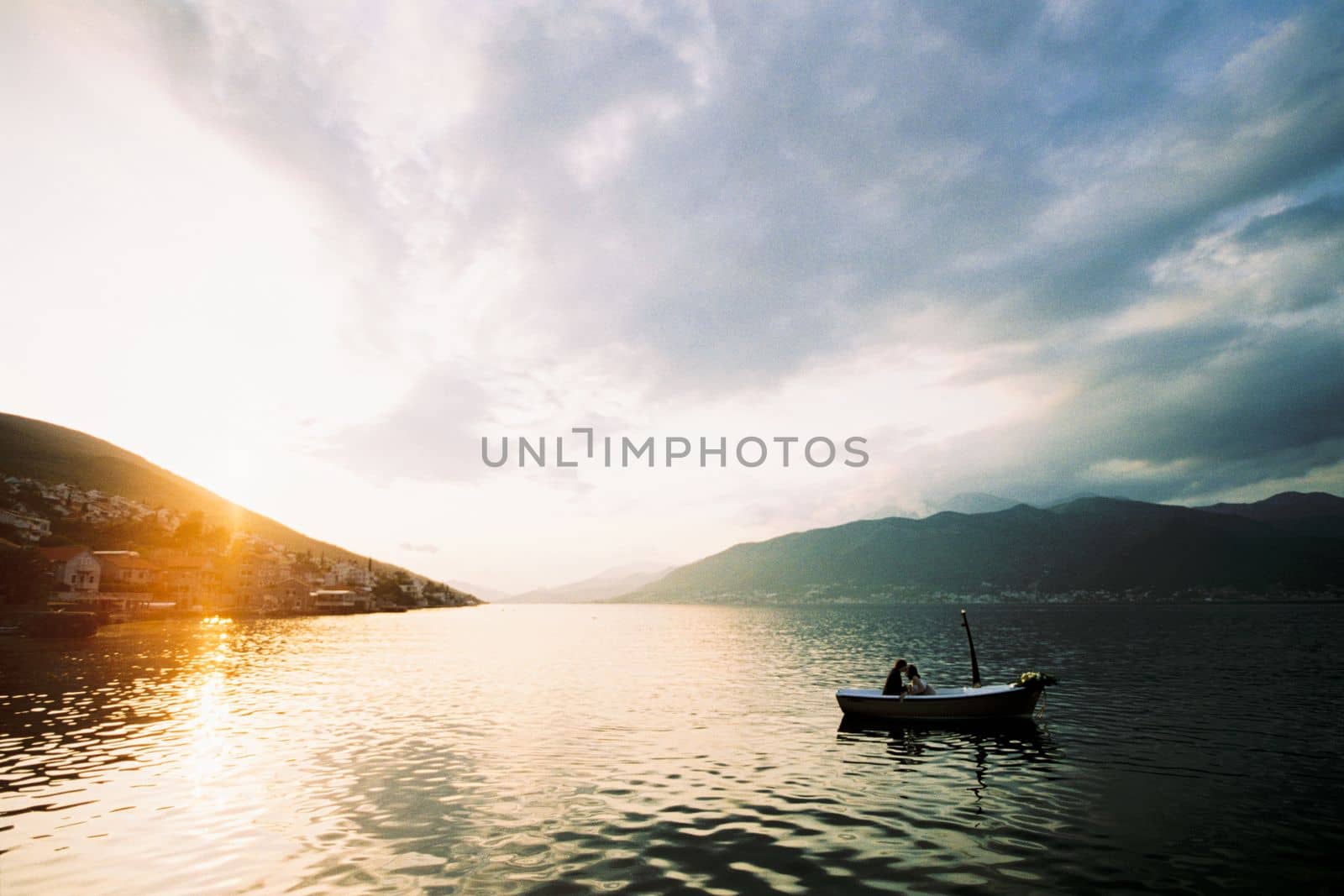 Man and woman kiss in a boat in the sea against the backdrop of mountains. High quality photo