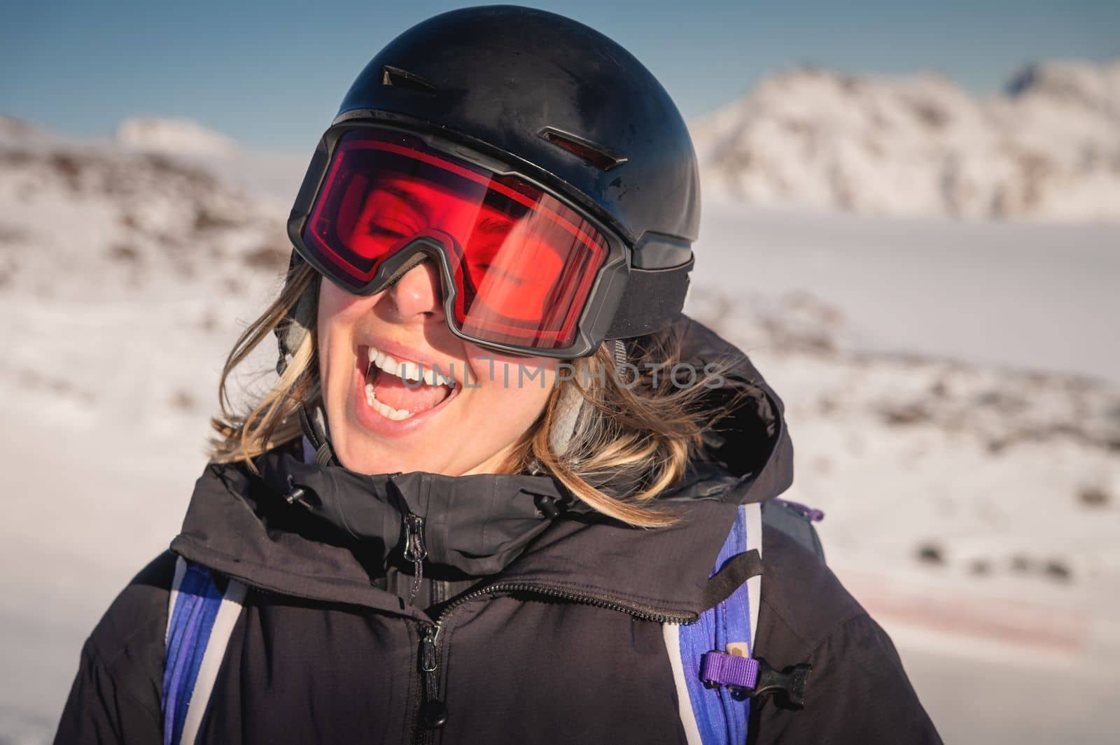Portrait of a woman in the Alps. Smiling young woman in ski goggles and helmet stopped while skiing in ski resort by yanik88