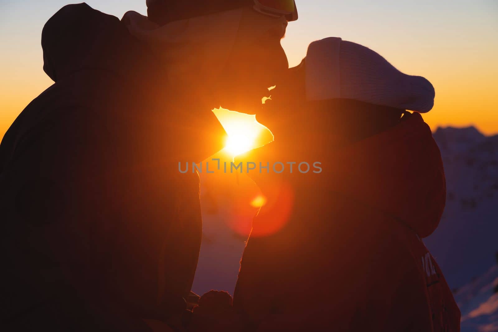 Silhouette of a couple kissing against the backdrop of sunset. Silhouette of a young couple loving each other against the backdrop of sunset. Couple in love at sunset in the mountains by yanik88